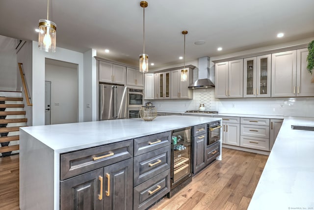 kitchen with wall chimney exhaust hood, gray cabinetry, stainless steel appliances, and pendant lighting