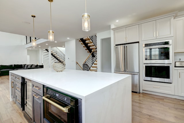 kitchen with stainless steel appliances, white cabinetry, hanging light fixtures, and a kitchen island