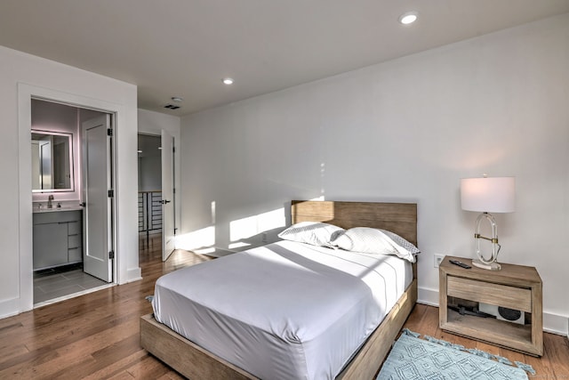 bedroom with hardwood / wood-style flooring, ensuite bathroom, and sink