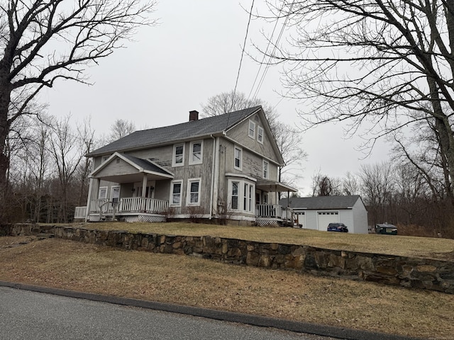 view of front facade featuring an outbuilding, a front yard, a porch, and a garage