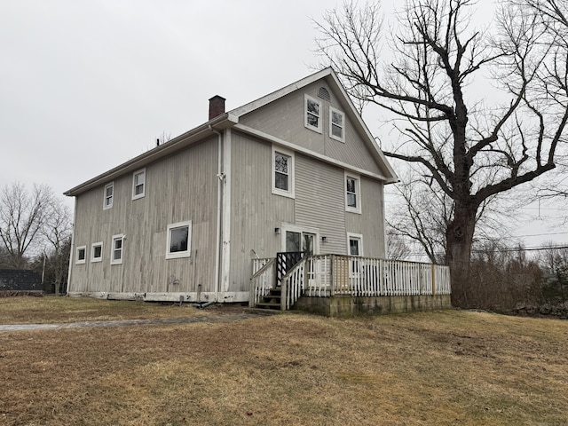 back of property featuring a wooden deck and a yard