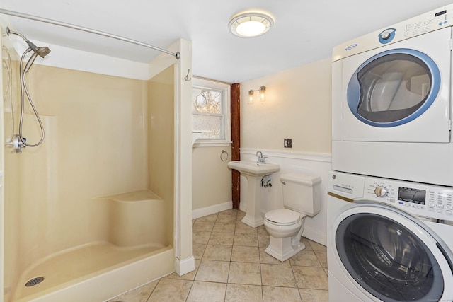 laundry area featuring stacked washer and clothes dryer and light tile patterned floors