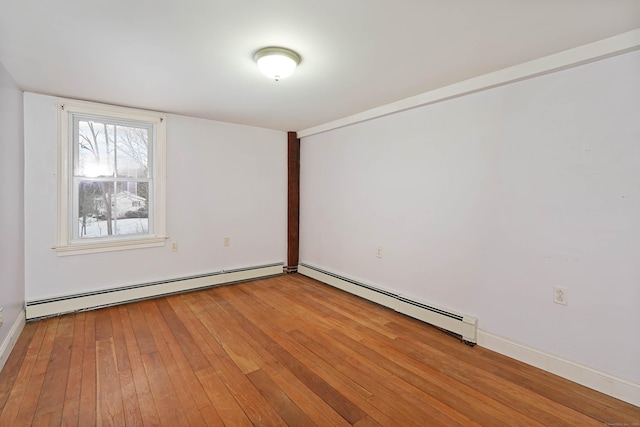 empty room featuring a baseboard heating unit and light hardwood / wood-style flooring