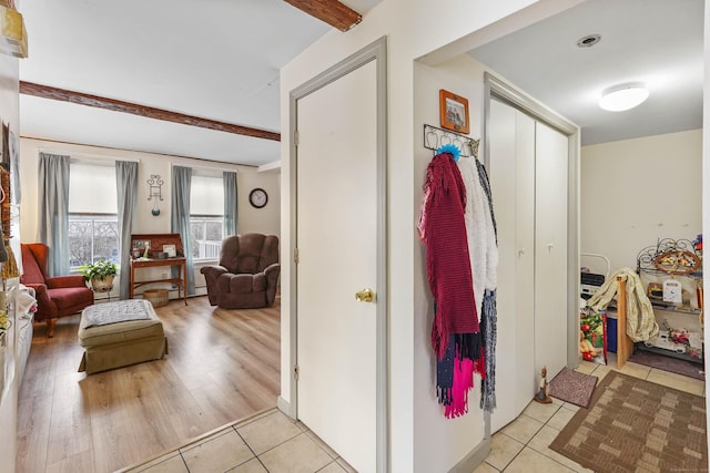 hallway featuring beamed ceiling and light tile patterned floors