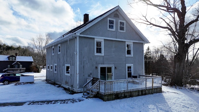 snow covered back of property featuring a deck