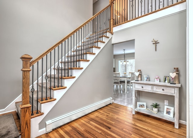 stairs featuring baseboard heating and wood-type flooring