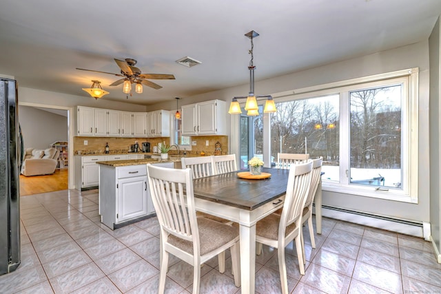 tiled dining room featuring sink, ceiling fan, and a baseboard heating unit