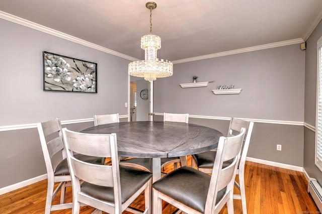 dining room featuring wood-type flooring, baseboard heating, a notable chandelier, and crown molding