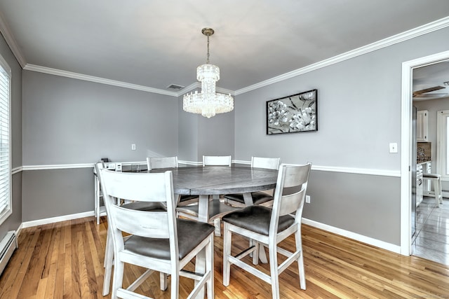 dining room with baseboard heating, hardwood / wood-style flooring, a chandelier, and ornamental molding