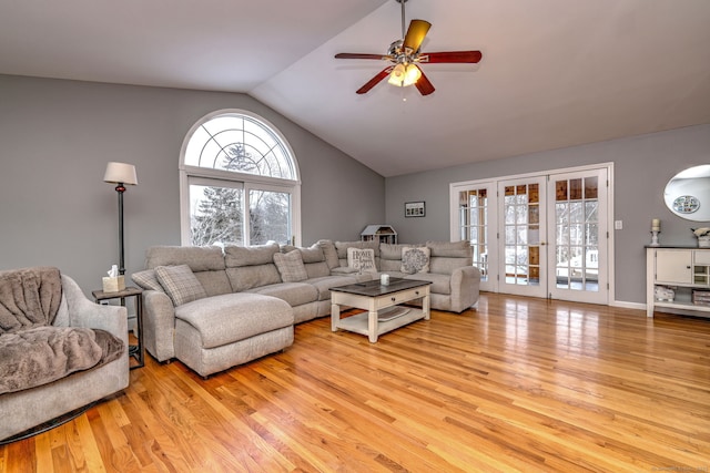 living room featuring light hardwood / wood-style flooring, vaulted ceiling, ceiling fan, and french doors