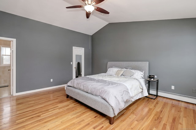 bedroom featuring baseboard heating, light wood-type flooring, ensuite bath, vaulted ceiling, and ceiling fan