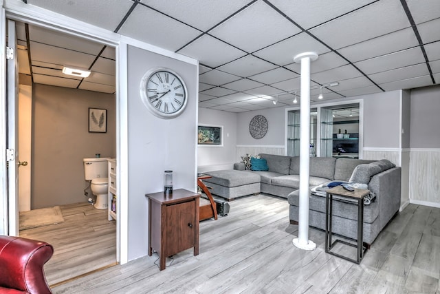 living room featuring a drop ceiling and light hardwood / wood-style flooring