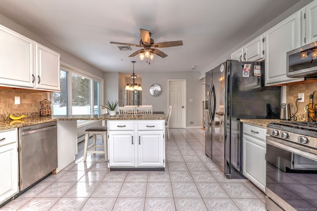 kitchen with light stone countertops, white cabinets, stainless steel appliances, and tasteful backsplash