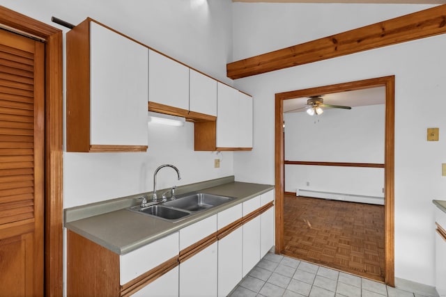 kitchen featuring ceiling fan, sink, light tile patterned flooring, white cabinetry, and baseboard heating