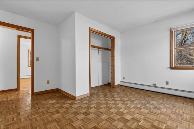 unfurnished bedroom featuring baseboard heating and light parquet floors