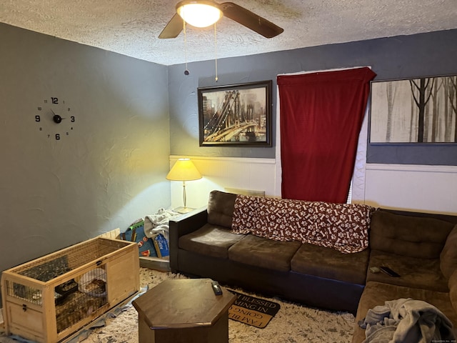 living room featuring ceiling fan and a textured ceiling