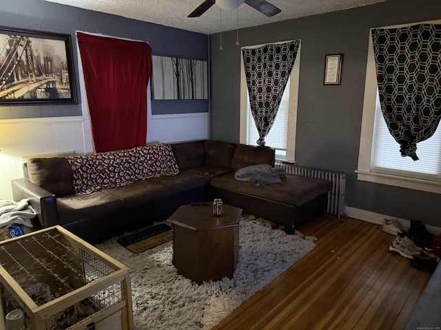 living room with a textured ceiling, radiator, wood-type flooring, and ceiling fan