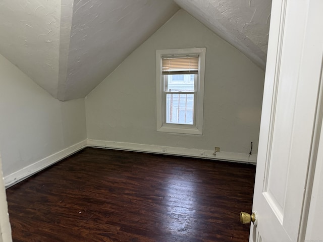 bonus room with a textured ceiling, lofted ceiling, and dark hardwood / wood-style floors