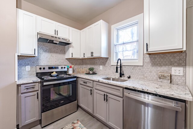 kitchen with light stone counters, sink, white cabinets, and appliances with stainless steel finishes