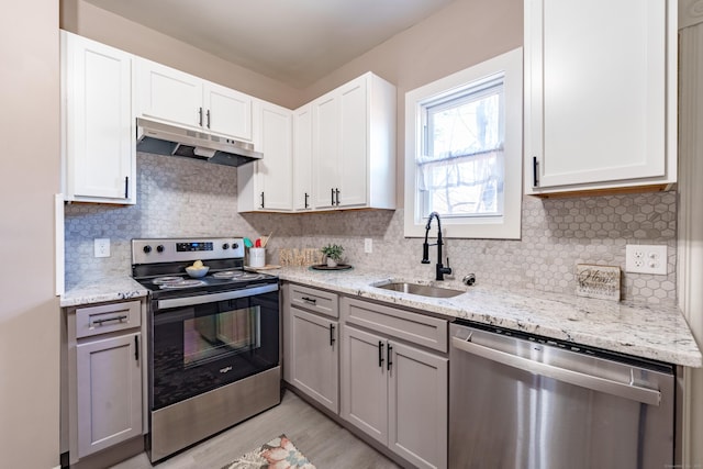 kitchen featuring stainless steel appliances, white cabinetry, light stone countertops, and sink