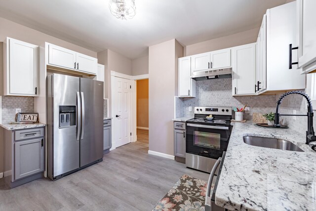 kitchen featuring white cabinets, sink, light stone counters, and stainless steel appliances