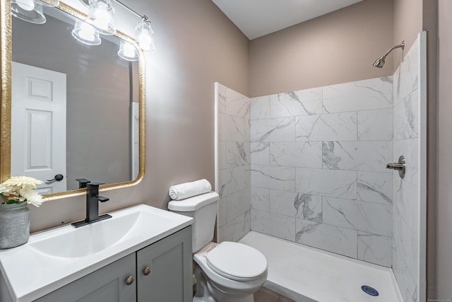 bathroom featuring toilet, vanity, and a tile shower