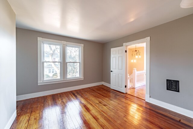 spare room featuring a chandelier and hardwood / wood-style floors