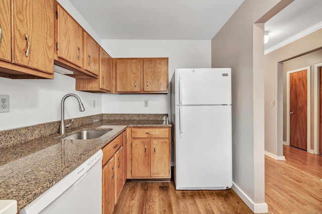 kitchen with white appliances, dark stone countertops, sink, ornamental molding, and light hardwood / wood-style flooring