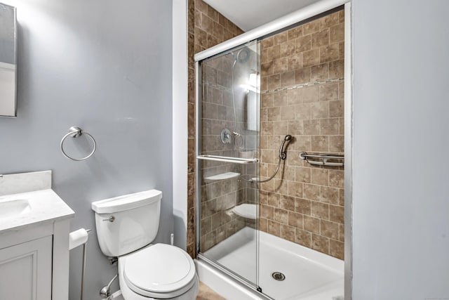 bathroom with toilet, an enclosed shower, and vanity