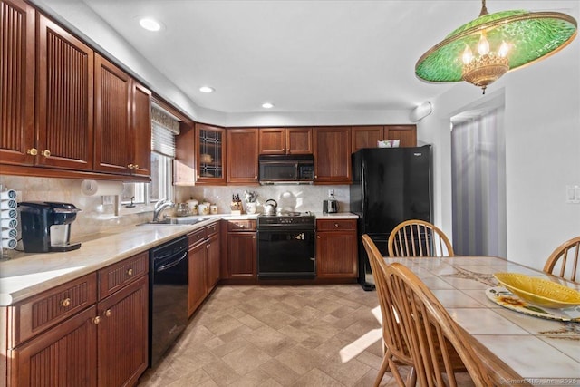 kitchen featuring sink, black appliances, pendant lighting, and decorative backsplash