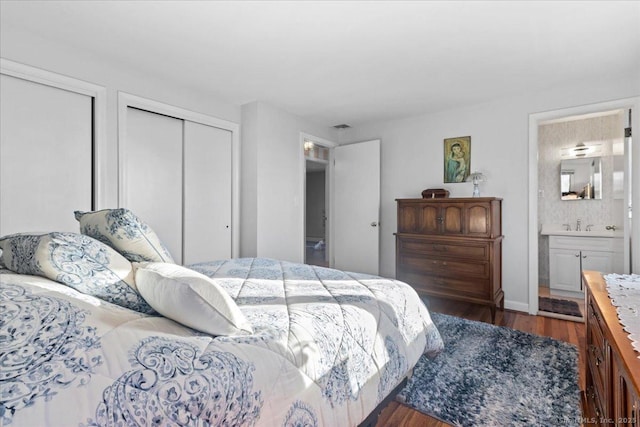 bedroom with ensuite bathroom and dark hardwood / wood-style flooring