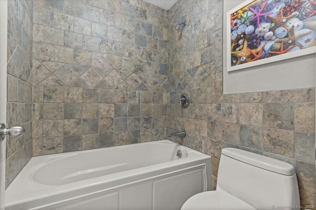 bathroom featuring tiled shower / bath combo, toilet, and tile walls