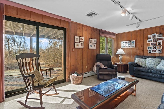 living room with rail lighting, a baseboard radiator, and wooden walls