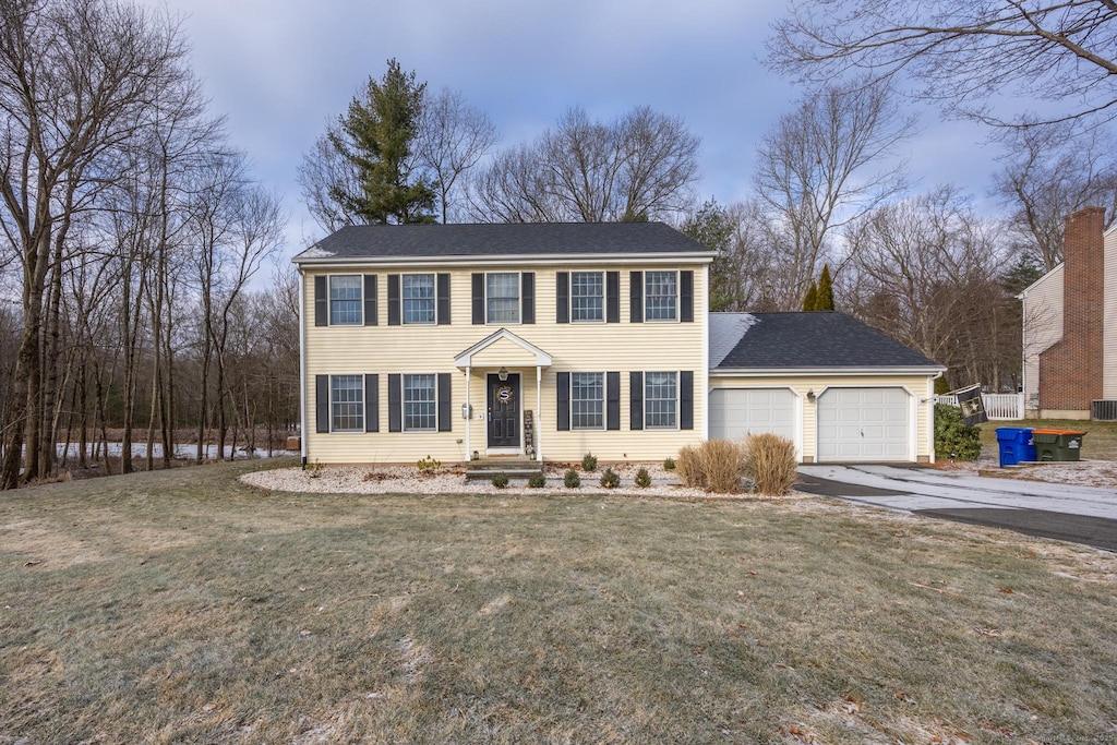 colonial home featuring a front yard and a garage