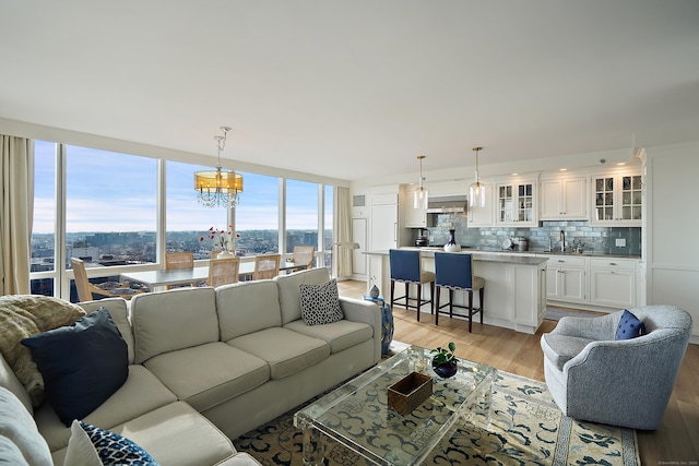 living room featuring a chandelier, light hardwood / wood-style flooring, and sink