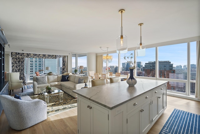 kitchen with pendant lighting, a center island, white cabinetry, a wall of windows, and light hardwood / wood-style floors