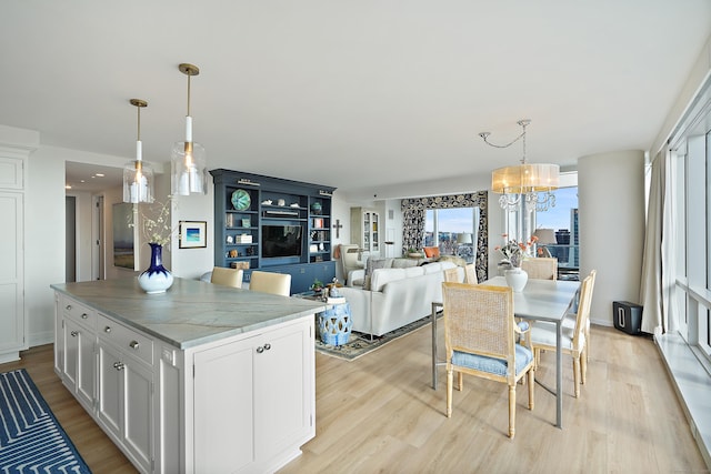 kitchen featuring pendant lighting, white cabinets, light hardwood / wood-style flooring, and a chandelier