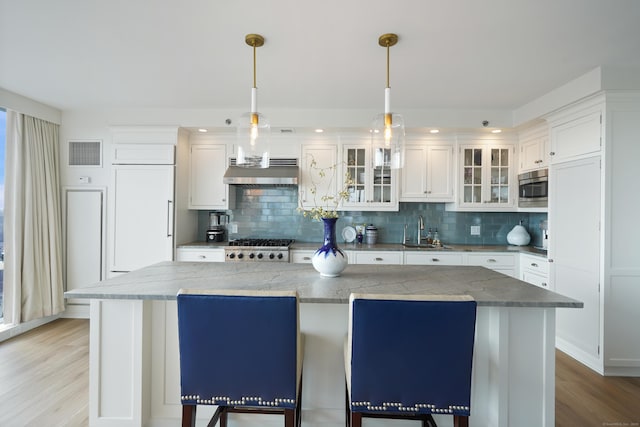 kitchen featuring appliances with stainless steel finishes, white cabinets, a kitchen island, and decorative light fixtures