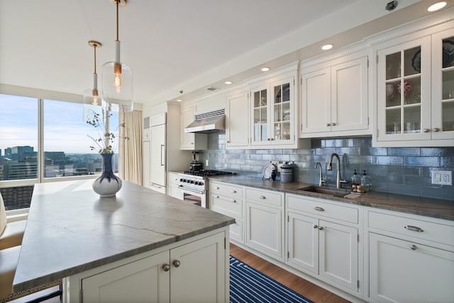 kitchen featuring premium appliances, hanging light fixtures, white cabinets, and tasteful backsplash