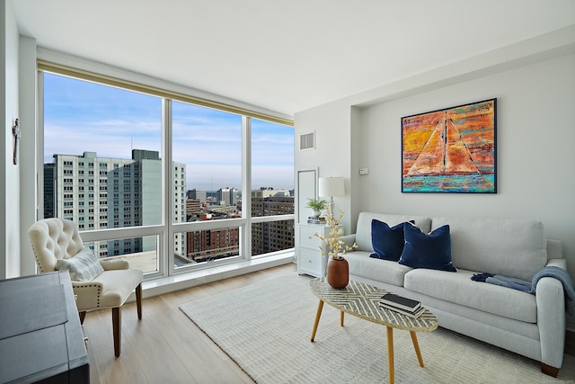 living room featuring a wealth of natural light, a wall of windows, and hardwood / wood-style flooring