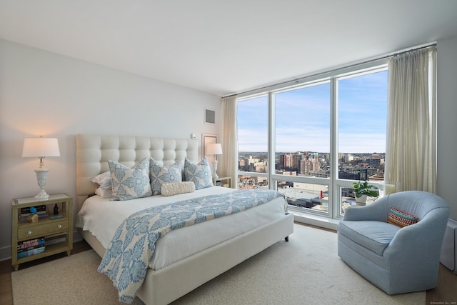 bedroom with hardwood / wood-style flooring and expansive windows