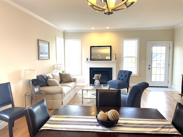 living room featuring an inviting chandelier, ornamental molding, and light hardwood / wood-style floors