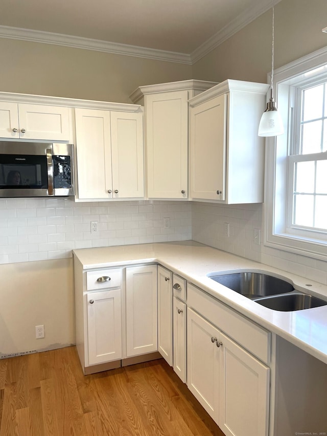 kitchen featuring white cabinetry, crown molding, backsplash, and light hardwood / wood-style floors