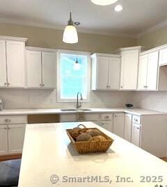 145 Webster Ln Unit 2-41, Middletown, CT 06457 - kitchen featuring decorative light fixtures, a sink, light countertops, white cabinets, and ornamental molding