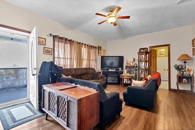 living room with ceiling fan, hardwood / wood-style floors, and a textured ceiling