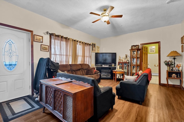 living room with ceiling fan, hardwood / wood-style floors, and a textured ceiling