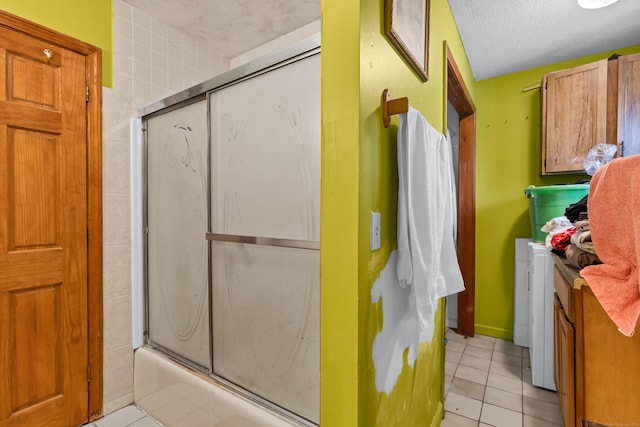 bathroom with bath / shower combo with glass door, vanity, a textured ceiling, and tile patterned flooring