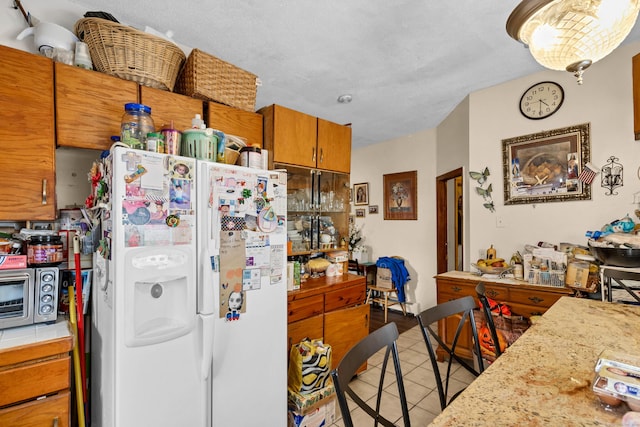 kitchen with white refrigerator with ice dispenser, light tile patterned floors, and a textured ceiling