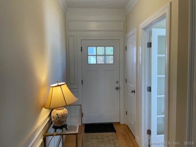 doorway to outside featuring crown molding and light hardwood / wood-style flooring