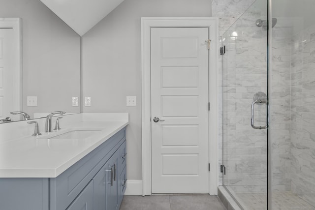 bathroom with vaulted ceiling, tile patterned floors, a shower with door, and vanity